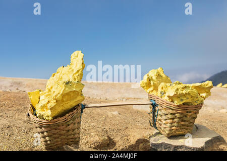 Cestello pesante laden da pezzi di zolfo naturale di trasportare dai minatori dal cratere miniera. Il lavoro manuale di zolfo intensivo sfruttamento delle miniere in Kawah Ijen. Foto Stock