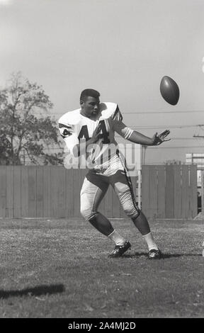 1964, storico, football universitario di Roses, estate e un giovane uomo nero in America che si allena con il pallone alla University of Southern California, Los Angeles, USA. Foto Stock