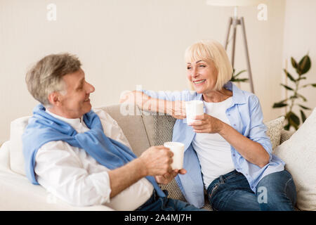 Felice coppia senior con tazzine di caffè seduti sul divano Foto Stock