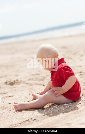 Bambino seduto sulla spiaggia Foto Stock