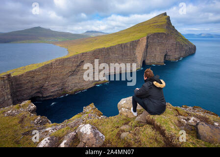 Escursionista guardando il lago Sorvagsvatn su isole Faerøer Foto Stock