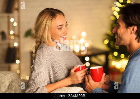 Amare giovane bere il tè nella parte anteriore dell albero di Natale Foto Stock