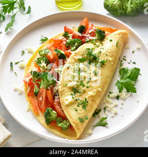 Omelette ripiene con pomodori, peperone rosso e broccoli luce sul tavolo di legno. Alimentazione sana alimenti per la colazione. Gustoso cibo di mattina. Foto Stock