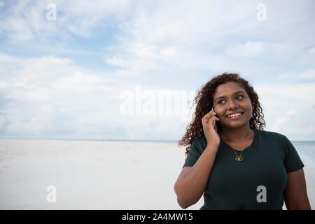 Donna che parla tramite telefono cellulare sulla spiaggia Foto Stock