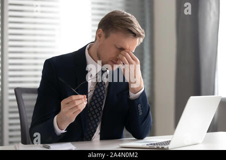 Uomo d'affari decollare occhiali, affetti da occhi secchi sindrome Foto Stock