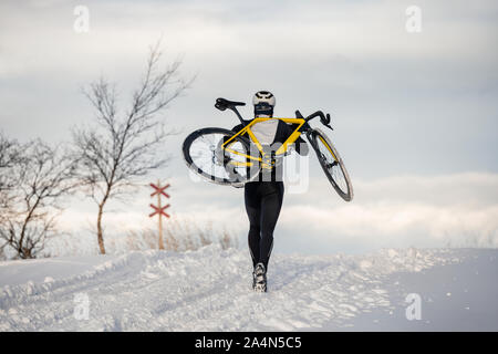 Uomo che porta bicicletta in inverno Foto Stock