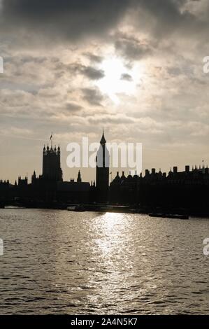 Silhouette del case del Parlamento contro un tramonto con il fiume Tamigi in primo piano il centro di Londra Inghilterra REGNO UNITO Foto Stock