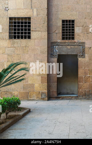 Esterno antico vecchi mattoni decorata muro di pietra con due finestre e porta aperta che conduce al periodo ottomano Beit El Sehemy edificio storico, il Cairo, Egitto Foto Stock