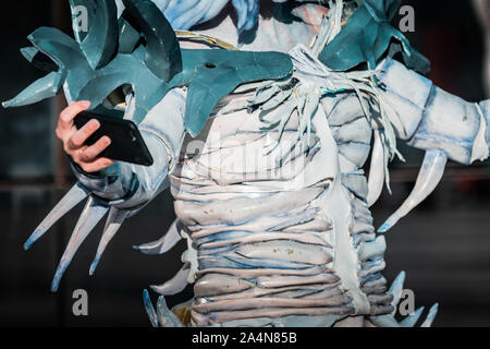 Selfie Zombie. Bianco morto nevoso regina costume, cosplayer ragazza con uno smartphone verso di sé. La luce naturale del giorno, ora d'oro di ripresa macro. Foto Stock