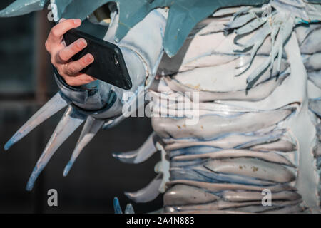 Selfie Zombie. Bianco morto nevoso regina costume, cosplayer ragazza con uno smartphone verso di sé. La luce naturale del giorno, ora d'oro di ripresa macro. Foto Stock