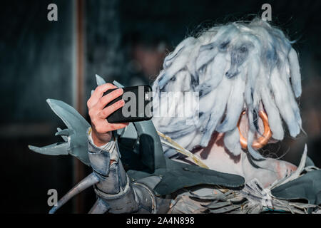 Selfie Zombie. Bianco morto nevoso regina costume, cosplayer ragazza con uno smartphone verso di sé. La luce naturale del giorno, ora d'oro di ripresa macro. Foto Stock
