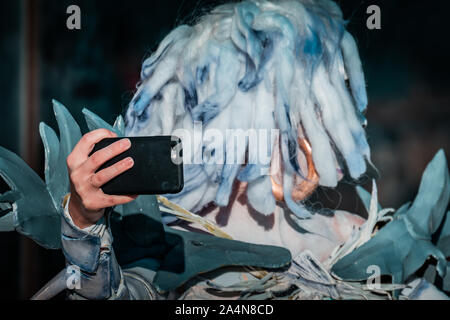 Selfie Zombie. Bianco morto nevoso regina costume, cosplayer ragazza con uno smartphone verso di sé. La luce naturale del giorno, ora d'oro di ripresa macro. Foto Stock
