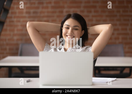 Sorridente Asian imprenditrice dipendente relax nel confortevole sedia da ufficio Foto Stock