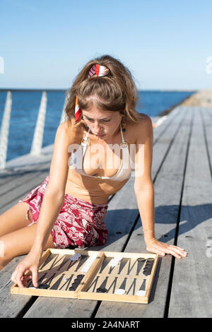 Giovane donna giocando Blackgammon sul molo Foto Stock