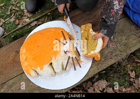 Ragazza con un coltello in mano il taglio della testa del suo gatto arancione torta di compleanno in un suo sesto compleanno al di fuori in Wales UK KATHY DEWITT Foto Stock