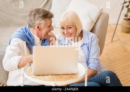 Felice Coppia matura la navigazione in Internet sul computer portatile e ridere Foto Stock