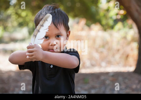 Un ragazzino che tiene una piuma Uccelli come una spada in una corona posizione di guardia. Foto Stock