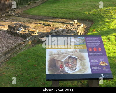 Il pannello delle informazioni che spiegano le fondamenta in pietra che può essere visto per i soldati latrina, parte del bagno romano-house a Bearsden fort. Foto Stock