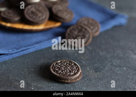 Biscotti al cioccolato con crema vaniglia riempimento nero su sfondo colorato. Foto Stock