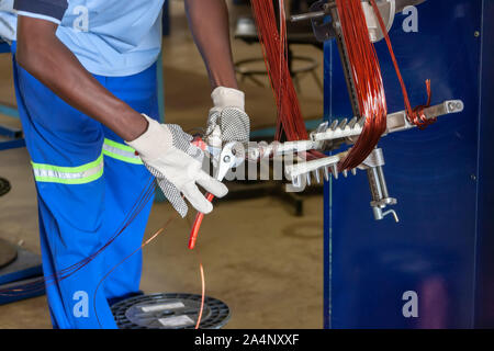 Lavoratore africano di eseguire le riparazioni in un motore elettrico, il riavvolgimento Foto Stock