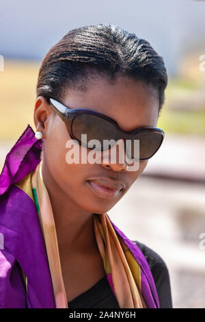 Motswana africana donna giovane, ritratto con occhiali da sole all'aperto in Botswana Foto Stock