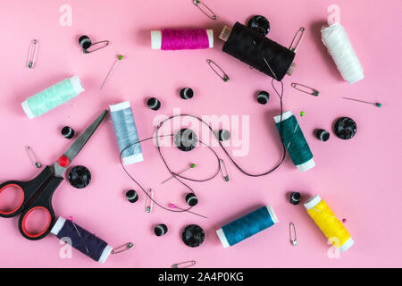 Composizione di coloratissimi accessori per il cucito sullo sfondo color pastello. Lay piatto. Vista dall'alto. Foto Stock