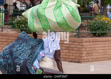 Donna africana sulla strada il trasporto di un carico di grandi dimensioni Foto Stock