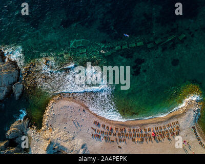 Vista aerea di Sveti Nikola, isola di Budva, Montenegro. Hawaii spiaggia, ombrelloni e bagnanti e acque cristalline. Coste frastagliate Foto Stock