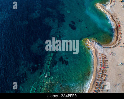 Vista aerea di Sveti Nikola, isola di Budva, Montenegro. Hawaii spiaggia, ombrelloni e bagnanti e acque cristalline. Coste frastagliate Foto Stock