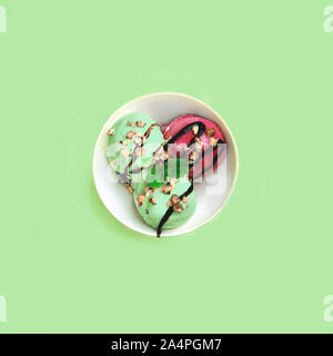 Il pistacchio e gelato alla fragola con caramello, dadi e menta sulla ciotola bianco su verde menta sfondo blu. Bellissimo il dessert. Scatto dall'alto. Appartamento laico, vista dall'alto. Close up, copia dello spazio. Foto Stock