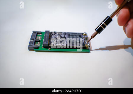 Le mani umane lavorando su chipset ssd componenti di computer con un cacciavite Foto Stock