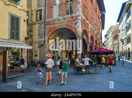 Scorcio del centro storico della famosa città di Pisa con i turisti in pedicab e caffetteria all'aperto in estate, Toscana, Italia Foto Stock