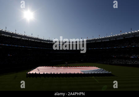 Bronx, Stati Uniti. 15 ottobre, 2019. New York Yankees e Houston Astros giocatori stand su linee di base come una gigantesca bandiera americana viene visualizzato nel campo centrale durante l'inno nazionale prima nel gioco 3 della American League Campionato di Serie allo Yankee Stadium il Martedì, Ottobre 15, 2019 a New York City. Gli Yankees e Astros sono legati al meglio delle 7 serie 1-1. Foto di Giovanni Angelillo/UPI Credito: UPI/Alamy Live News Foto Stock