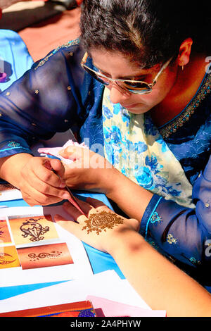 Donna asiatica di verniciatura di un design henné su una giovane donna di mano. Foto Stock