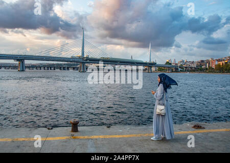 Bagno turco donna in piedi sull'Istanbul foreshore. La metro e i ponti di Ataturk in background Foto Stock