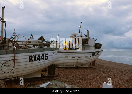 Hastings, East Sussex, Regno Unito. Il 15 ottobre 2019. Pescatori tendono le loro reti all'alba, su nuvoloso ottobre mattina. Foto Stock