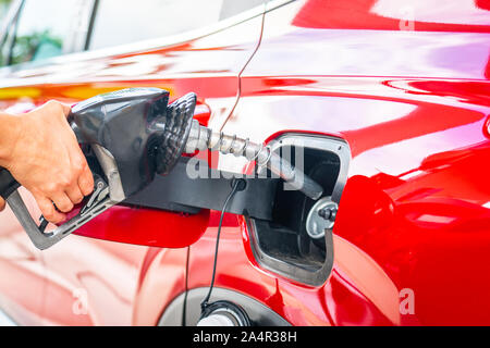 Mano con pistola del carburante con la nuova vettura in background Foto Stock