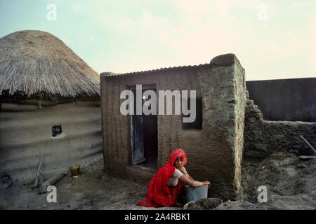 04 Mar 2020 donna applicare fango e gesso di sterco di vacca sulla parete della casa Sri Dungargarh Bikaner Distretto Rajasthan India Foto Stock