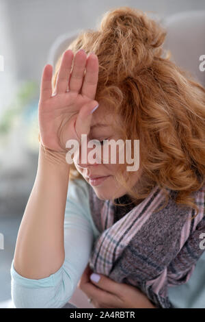 Donna di toccare la fronte mentre sensazione sotto meteo Foto Stock