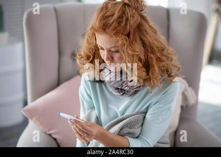 Sentimento donna triste dopo la misurazione della temperatura corporea Foto Stock