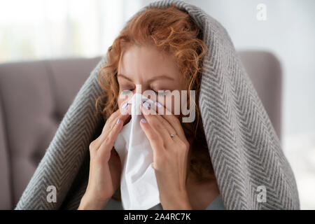 Donna di chiudere gli occhi mentre si starnutisce e aver acceso il naso Foto Stock