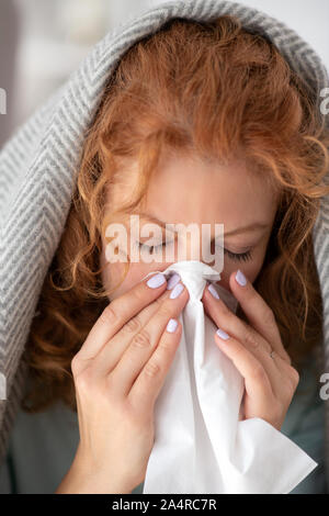 La donna coperta in plaid tenendo igienico pur avendo naso chiuso Foto Stock