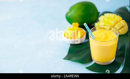 Giallo mango yogurt o frullati su sfondo blu con copia spazio a sinistra. Curcuma Lassie o lassi in vetro. Banner Foto Stock