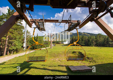 In Kirghizistan, Karakol ski resort - Agosto 22, 2019. Estate paesaggio di montagna in alta montagna. Alberi di alto fusto di alberi di Natale, ski-lift a sci Foto Stock