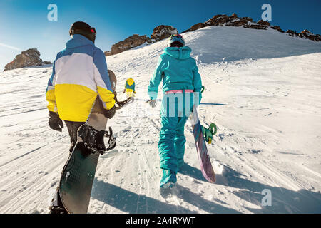 Tre amici snowboarder va in salita con gli snowboard in mani per il backcountry o free ride. Ski tour concept con il gruppo dei popoli Foto Stock
