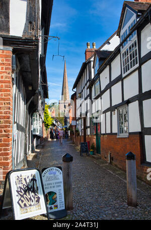 Edifici storici incorniciati in legno sullo stretto viale acciottolato della chiesa con San Michele e la chiesa di tutti gli Angeli sullo sfondo, Ledbury, Herefordshire, Inghilterra Foto Stock