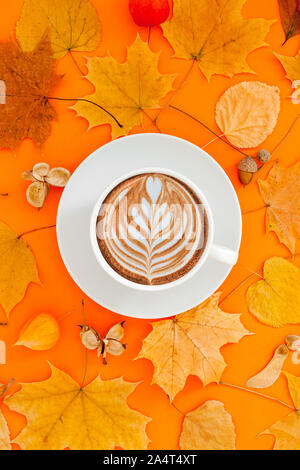 Autunno piatto composizione laici con foglie secche ghirlanda di telaio e caffè latte cup sul bold orange Colore di sfondo. Creative autunno, ringraziamento, caduta, ha Foto Stock