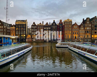 Amsterdam, Paesi Bassi - Ottobre 2,2019: Amsterdam canal Singel con tipiche case olandese e case galleggianti, barche in serata con acqua bella ri Foto Stock