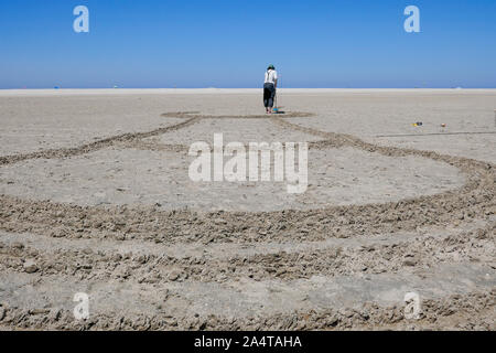 Creazione di disegni di sabbia in spiaggia in Olanda Foto Stock