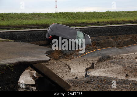 Mito per la città, Giappone. 15 ottobre, 2019. Una vettura si stacca una strada distrutta dalle inondazioni.Il numero di morti sale a 48, due giorni dopo il tifone Hagibis passata attraverso il Giappone mentre 15 sono ancora mancanti e più di un centinaio di feriti come migliaia di truppe militari in missioni di soccorso in tutto il paese. Credito: SOPA Immagini limitata/Alamy Live News Foto Stock